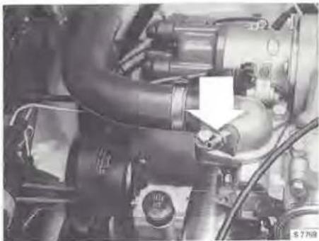 Close-up of an automotive engine bay with hoses and control knobs (no visible text or symbols)