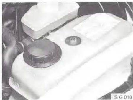 Close-up of a white automotive engine compartment with a black valve and circular component (no visible text or symbols)