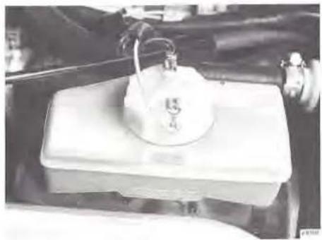 Close-up of a white car engine compartment with a small cylindrical component on top (no visible text or symbols)