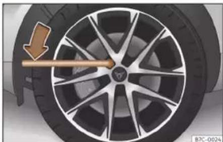 Close-up of a car wheel rim with a wooden arrow indicating clockwise motion (no text or symbols)