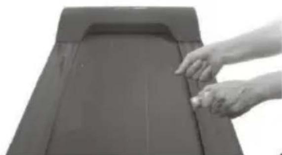 Close-up of hands placing a small object on a dark, rectangular surface (no text or symbols visible)