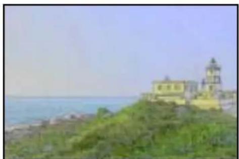Coastal view with a lighthouse on a rocky hill overlooking the sea under a clear sky (no visible text or symbols)