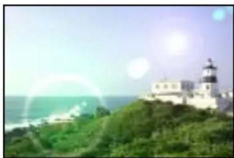 Scenic coastal view with lighthouse on hilltop, ocean and bright sky in background (no text or symbols visible)