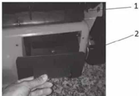 Close-up photo of a hand holding a black plastic component with labeled parts 1 and 2