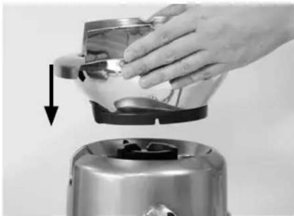 Close-up of a hand pressing down on a metallic appliance with a downward arrow indicating motion (no text or symbols visible)