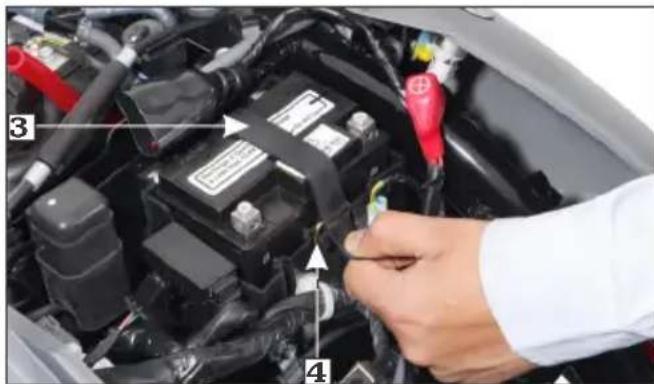 Close-up of a car engine bay with numbered annotations pointing to components like battery, switch, and wiring.
