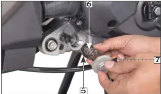 Close-up of a hand adjusting a mechanical component with numbered parts labeled 5, 6, and 7.