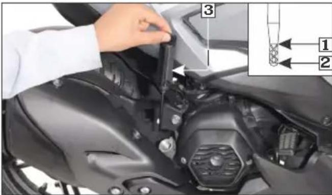 Instructional image showing a hand adjusting a component on a motorcycle's engine, with labeled parts 1 and 2.