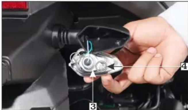 Close-up of a hand inserting an electric vehicle plug into a car, with numbered annotations pointing to the plug.