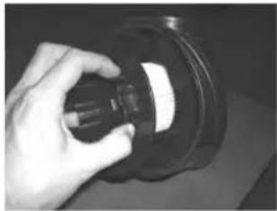 Hand holding a black cylindrical object with a white label, no visible text or symbols