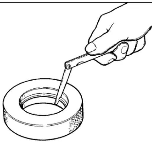 Line drawing of a hand using a tool to lift a circular tire (no text or symbols)