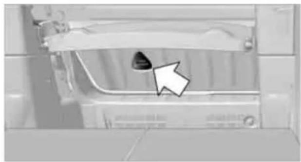 Close-up of a mechanical component with a black arrow pointing to a small dark object, no visible text or symbols.