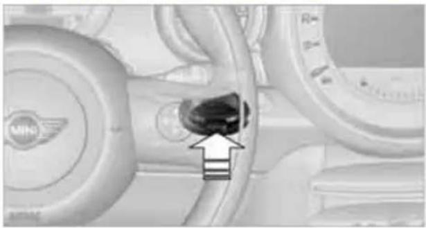 Close-up of a car interior showing a highlighted engine component with an arrow pointing to it (no text or symbols visible)