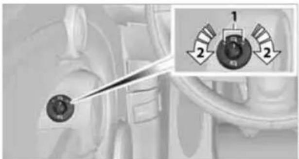 Close-up of a mechanical component with a pointed tool and two circular adjustment knobs labeled 1 and 2 (no text or symbols on the main subject)