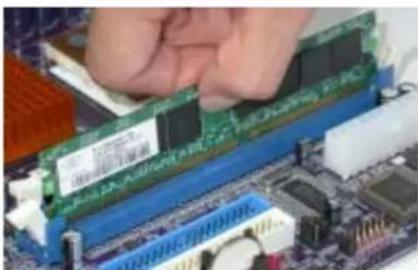 Close-up of hands installing a green RAM module on a computer motherboard (no visible text or symbols)