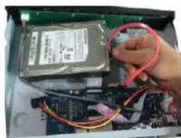 Close-up of hands connecting a hard disk to an electronic circuit board with wires (no visible text or symbols)
