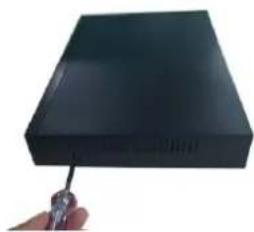 Hand holding a black rectangular device with a screwdriver inserted (no visible text or symbols)
