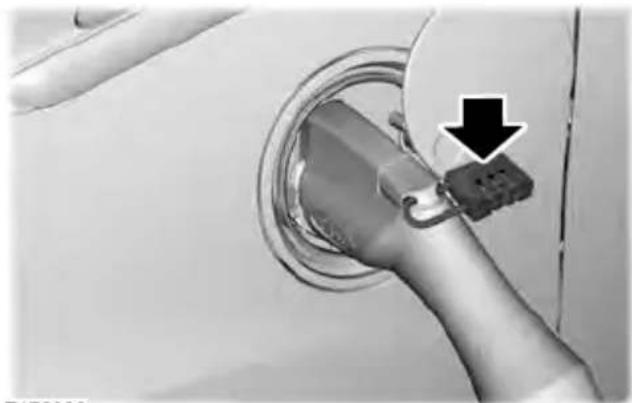 Close-up of a car's electrical plug with a black arrow pointing to a component (no text or symbols visible)