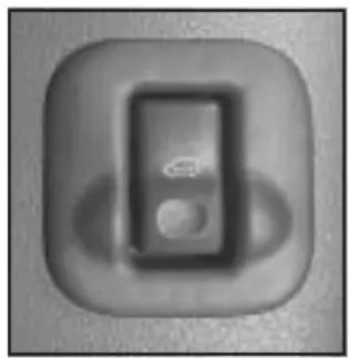 Close-up of a button with a circular icon and a small white symbol, no visible text or symbols.