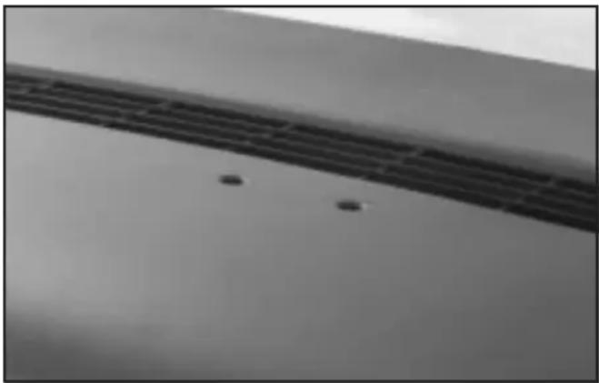 Close-up of a curved surface with two small dark spots, possibly indicating defects or features (no text or symbols visible)
