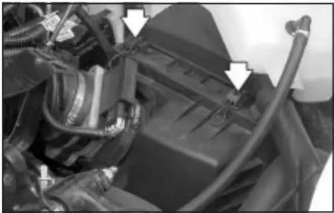 Close-up of automotive engine components with visible hoses and wiring (no text or symbols)