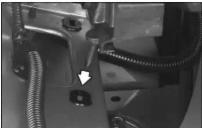 Close-up of a mechanical component with coiled tubing and a white arrow pointing to a small square feature (no visible text or symbols)