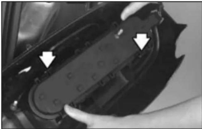 Close-up of hands adjusting a mechanical component with arrows pointing to features (no visible text or symbols)