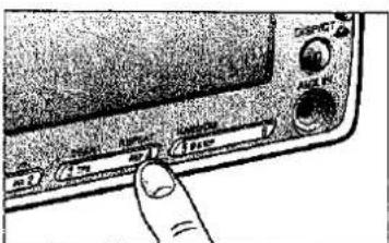 Close-up of a handheld electronic device with labeled buttons and a finger pointing to the control panel.