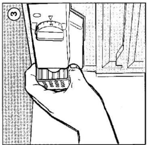 Hand holding a digital measuring device with a rotary dial and scale markings, showing a test setup with numbered parts.