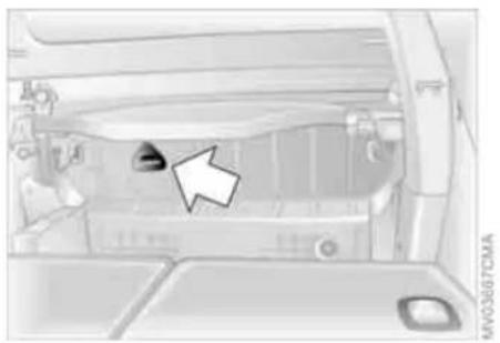Interior view of a car showing the hood, dashboard, and engine compartment with a white arrow pointing to a component (no text or symbols visible)