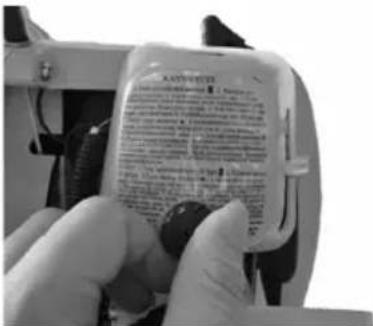 Close-up of a hand holding a small electronic device with printed text and a black button, likely from an electronics or automotive product.