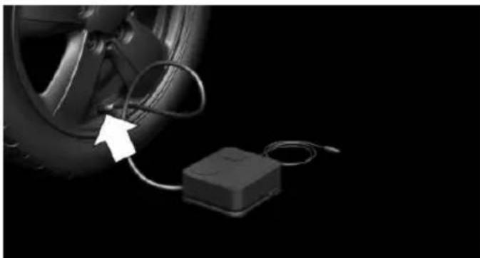 Close-up of a car tire connected to a small electronic device with cables, against a black background (no text or symbols visible)