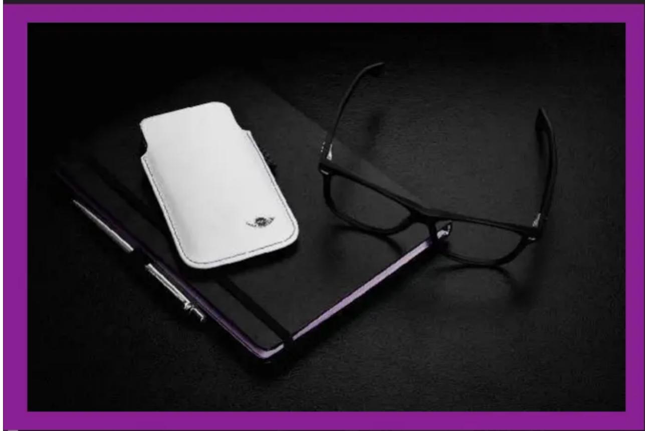 Black-and-white photo of eyeglasses and a white wallet on a dark surface, no text or symbols visible.