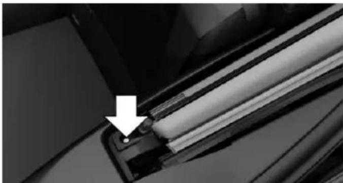 Close-up of a mechanical component with a white arrow pointing to a small circular feature (no text or symbols visible)