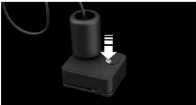 Close-up of a black cylindrical device with a white arrow pointing to a small button, against a black background (no text or symbols)
