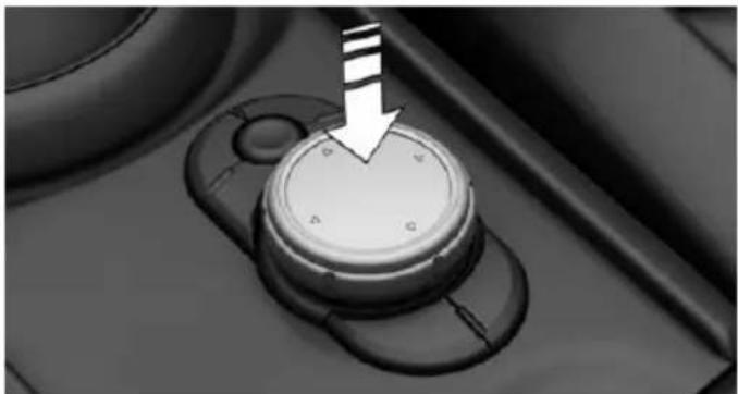 Close-up of a car dashboard knob with a white arrow pointing downward (no text or symbols visible)