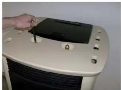 Hand inserting a small electronic device into a white appliance (no visible text or symbols)