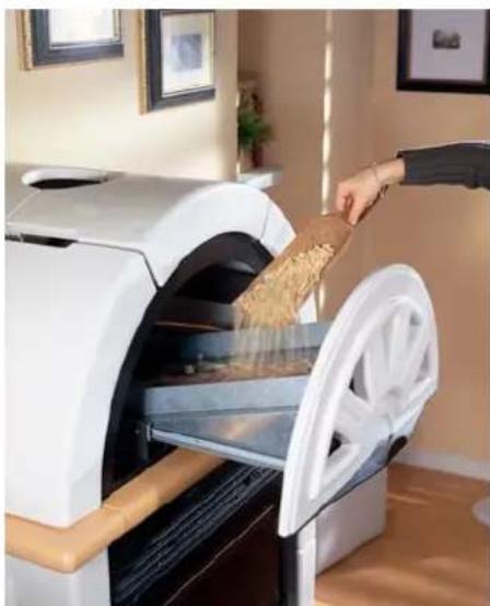 Person pouring food into a modern oven with a large wheel, in an indoor setting (no visible text or symbols)