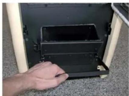 Hand placing a black plastic component into a white frame on a textured surface (no text or symbols visible)