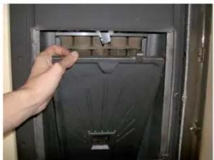 Hand placing a small electronic component into a black panel inside an open electrical cabinet (no visible text or symbols)