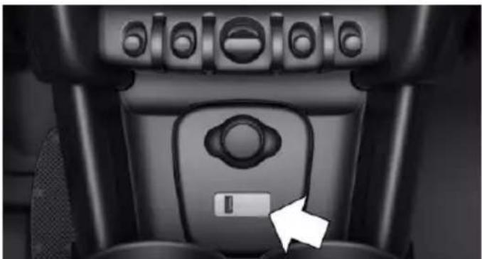Close-up of a black mechanical device's side panel with control knobs and a white arrow pointing to a button (no text or symbols visible)
