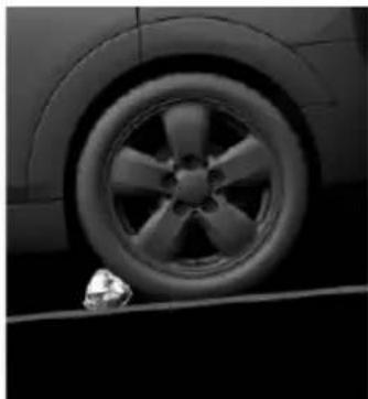 Close-up of a car wheel rim and rear wheel, with a small metallic object partially visible on the side (no text or symbols)