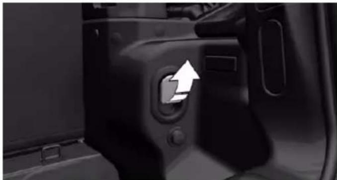 Close-up of a car door panel with a white arrow pointing to the door handle (no text or symbols visible)