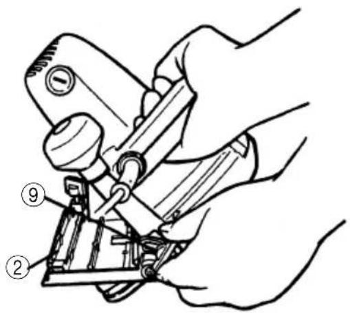Technical diagram showing hands operating a mechanical device with numbered parts labeled ② and ⑨