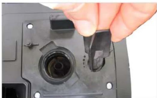 Close-up of a hand inserting a plastic component into a black plastic housing, no text or symbols visible.