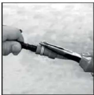 Close-up of a hand holding a small mechanical tool against a textured background (no visible text or symbols)