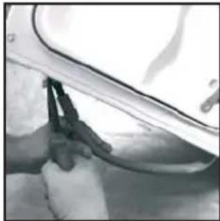 Close-up of hands using a tool to clean or inspect the surface of a vehicle (no visible text or symbols)