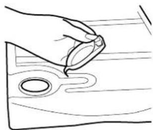 Line drawing of a hand holding a small object over a wooden surface with a circular hole (no text or symbols)