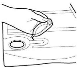 Line drawing of a hand holding a small object over a wooden surface with circular holes (no text or symbols)