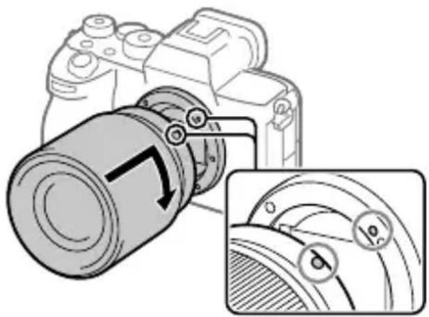 SONY Alpha A7S III - Podczas wyrównywania białych znaczników indeksowych (wskaźników mocowania) delikatnie dociskaj obiektyw do aparatu. Następnie obracaj obiektyw powoli zgodnie z kierunkiem strzałki, aż usłyszysz kliknięcie. - 1
